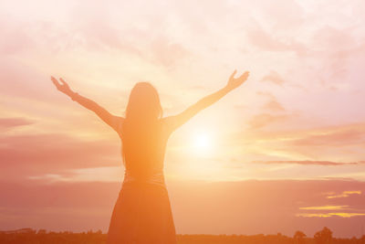 Silhouette woman standing by tree against sky during sunset