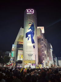 People on illuminated street amidst buildings in city at night