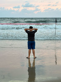 Rear view of woman standing at beach