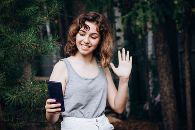 Beautiful teenager girl talking with friends by video call at the forest. girl taking a selfie
