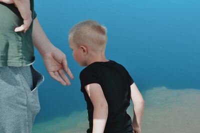 Rear view of father and son standing in water