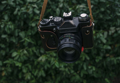 Close-up of camera hanging against plants