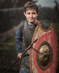 Smiling young woman in warrior costume standing outdoors