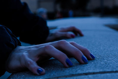 Close-up of woman hands on retaining wall in city during dusk