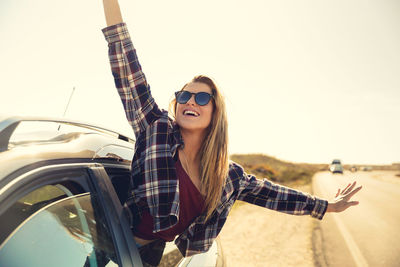 Young man with sunglasses on car against sky