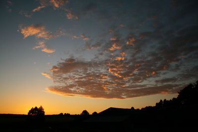 Silhouette trees against dramatic sky during sunset
