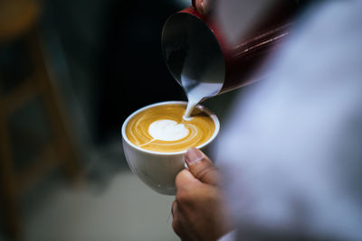 Cropped hand making coffee at cafe