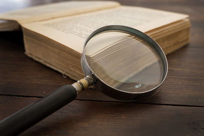 High angle view of magnifying glass with old book on table