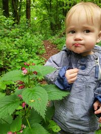 Portrait of cute baby boy standing by plants