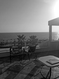 Chairs and table on beach against clear sky