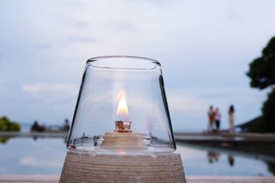 Close-up of oil lamp against swimming pool