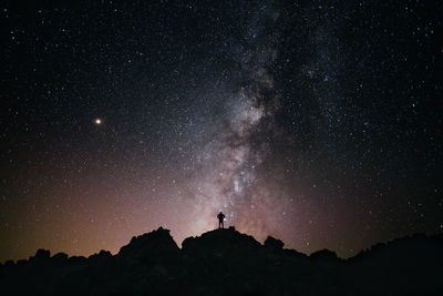 Silhouette person standing against star field at night