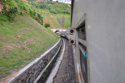 Car on road amidst field seen through train window