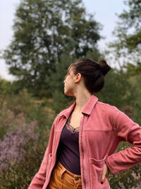 Woman looking away while standing against plants