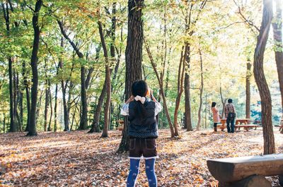 Girl standing near tree trunk in forest