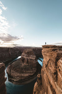 Man standing on rock formations against sky