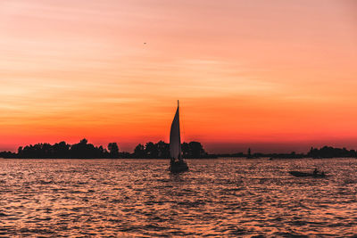 Silhouette of sailboat in sea during sunset