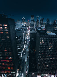 High angle view of illuminated street amidst buildings in city at night