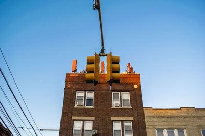 Low angle view of building and traffic light against clear blue sky.