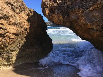 Rock formation on beach against sky