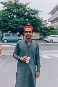 Portrait of young man standing on road in city