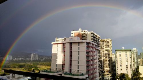 Rainbow over buildings in city against sky