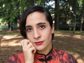 Close-up portrait of young woman against trees