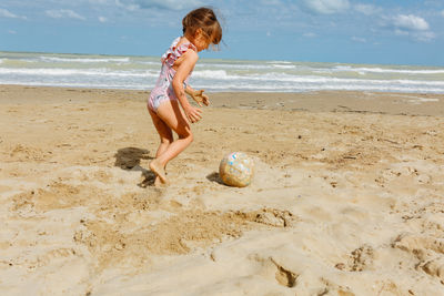 Rear view of girl playing with ball at beach