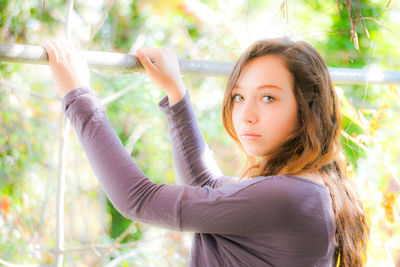 Portrait of young woman standing against tree