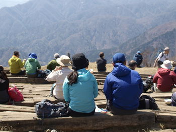 Rear view of people sitting on mountain
