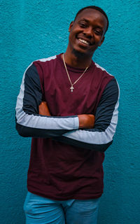 Portrait of a smiling young man standing against blue wall
