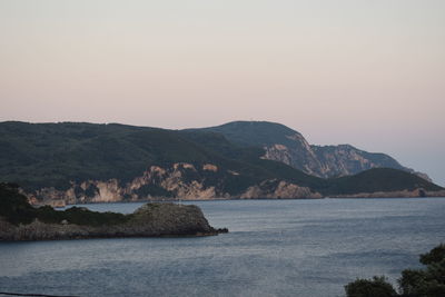 Scenic view of sea and mountains against clear sky