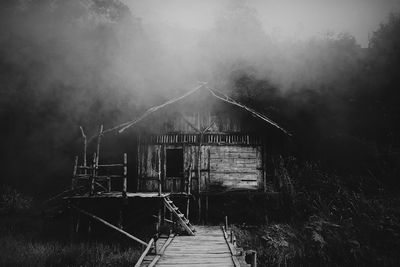 Abandoned house by building against sky