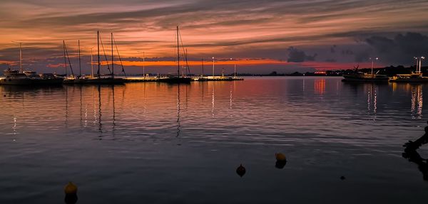 Sailboats moored on sea against sky during sunset