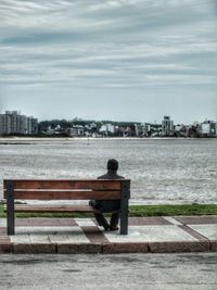Rear view of man sitting on riverbank