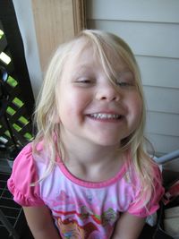 Close-up portrait of cheerful girl sitting by wall