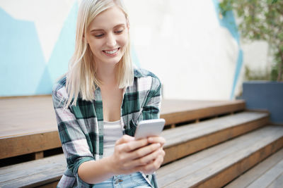 Smiling young woman using mobile phone