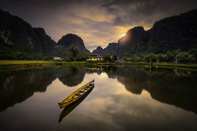 Boat in lake against sky during sunset