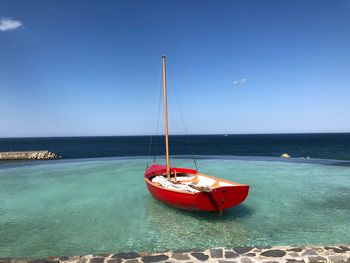 Sailboat moored on sea against clear blue sky