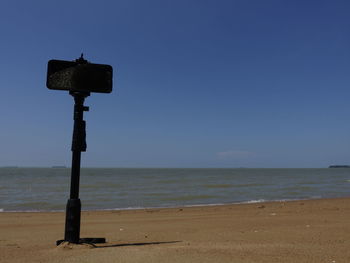 Information sign on beach against clear sky