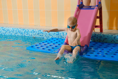 Toddler child learning to dive in indoor swimming pool with teacher. fun and action, splash