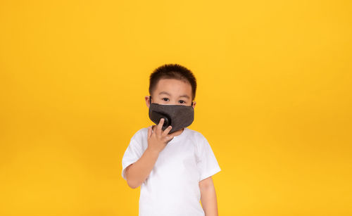Portrait of boy standing against yellow background