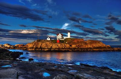 Building on rock formation at sea against sky