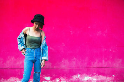 Portrait of young man standing against pink wall