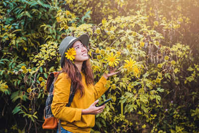 Smiling woman standing by flowering plant