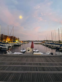 Sailboats moored at harbor during sunset