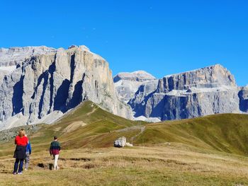 Rear view of people on mountain against clear blue sky