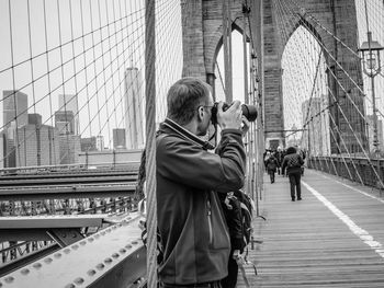 People photographing on bridge in city