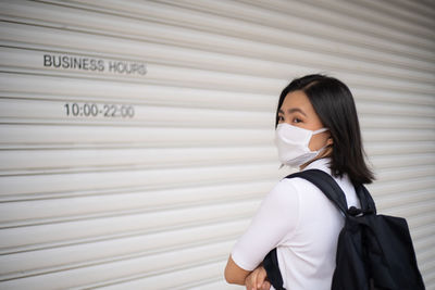 Full length of woman standing against closed shutter