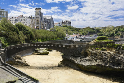 Arch bridge over river against buildings in city